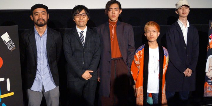 DirAct workshop ディラクト ワークショップ - ステージ前に黒系スーツとカジュアル衣装の男女5人が横一列、左看板の映画表示と演技の手法を学ぶスクール風