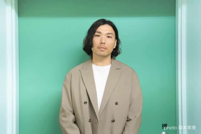 DirAct workshop ディラクト ワークショップ - 緑の背景に立つベージュのコートを着た俳優の演技練習風景とスクールの学び